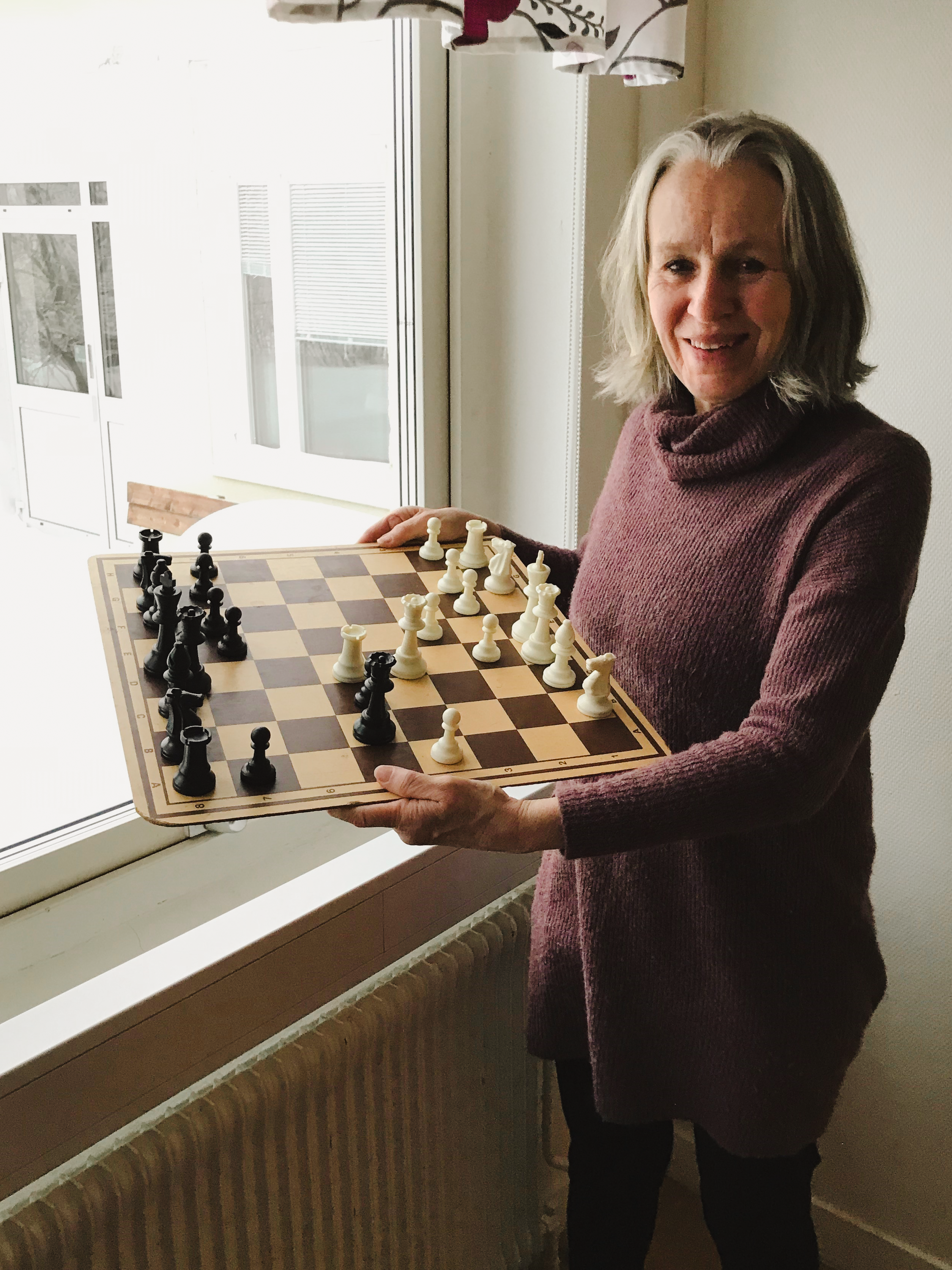 Ruth Ranberg håller i ett schackbräde med pjäser på och tittar in i kameran med ett leende.