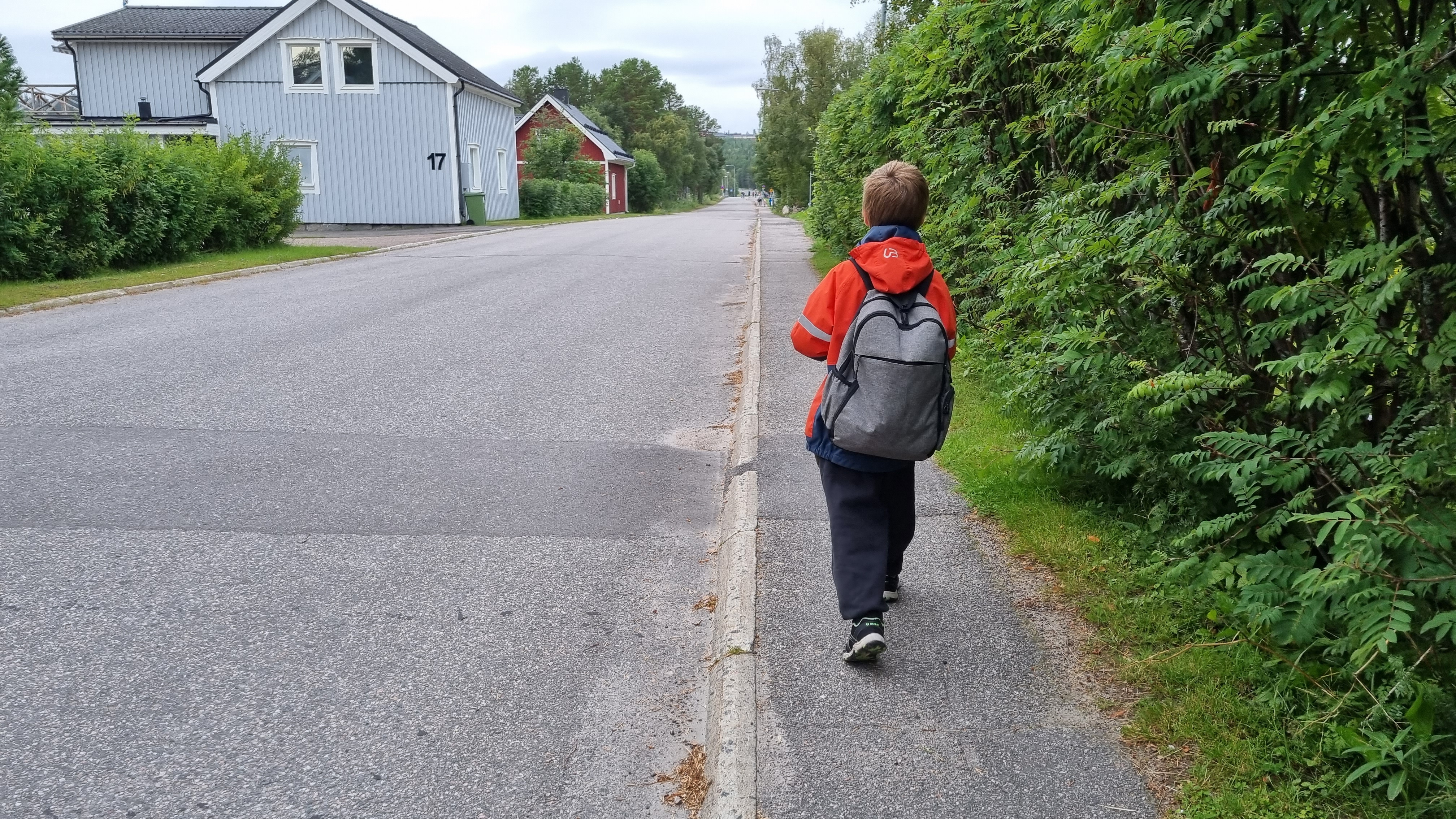 En pojke med stor ryggsäck på väg till skolan.