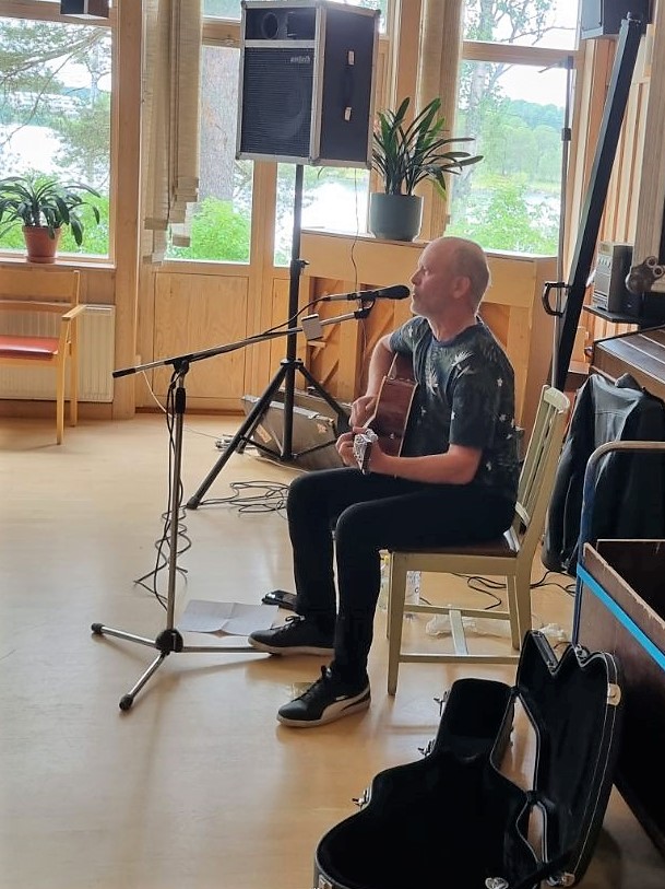 Tommy Holmström spelar gitarr och sjunger i Vaukagårdens samlingssal